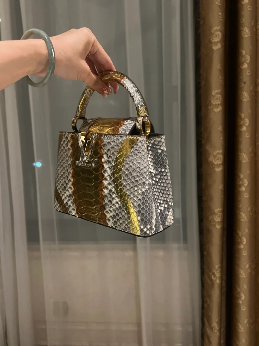 Сумка Capucines в руке, ракурс три четверти с логотипом LV