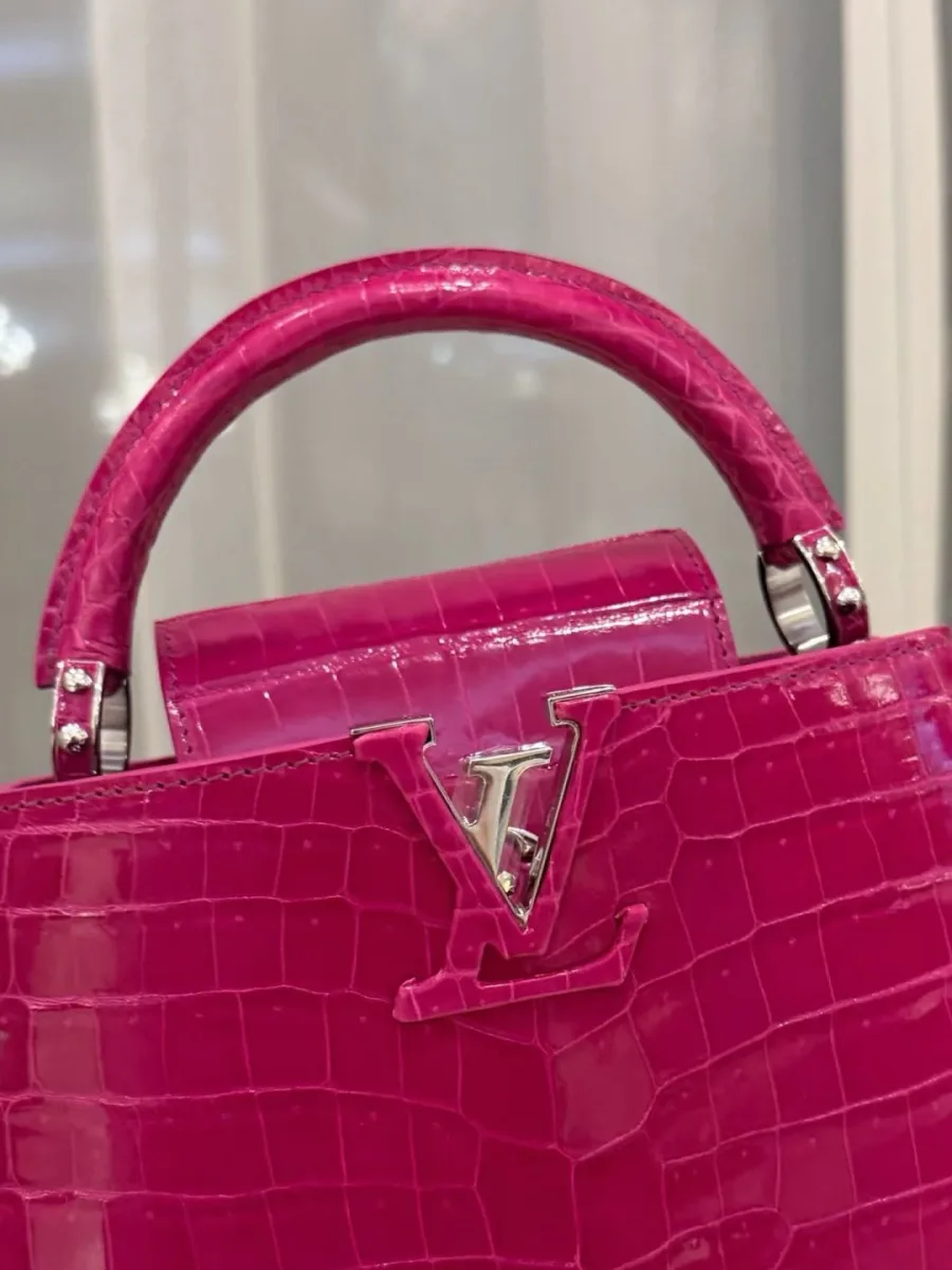 Крупный план серебристой монограммы LV и ручки розовой сумки
