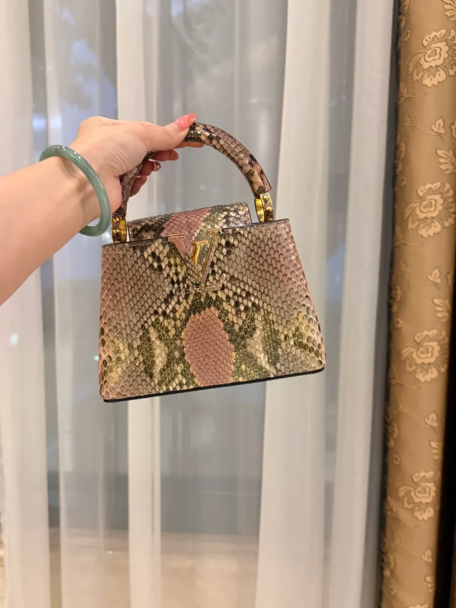 Розовая сумка Capucines из кожи змеи, вид спереди с золотистым логотипом