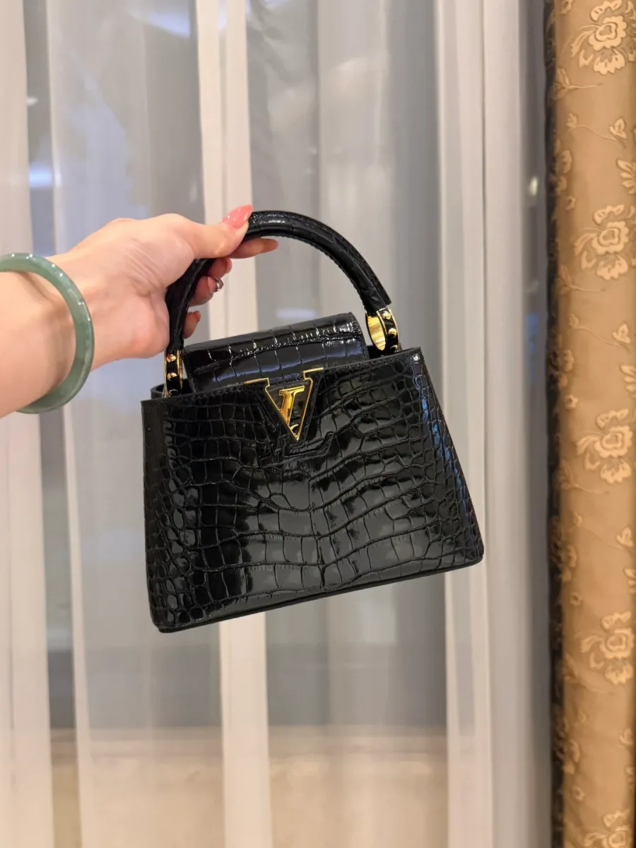 Чёрная сумка Capucines BB из кожи крокодила с верхней ручкой и золотистым логотипом, вид спереди