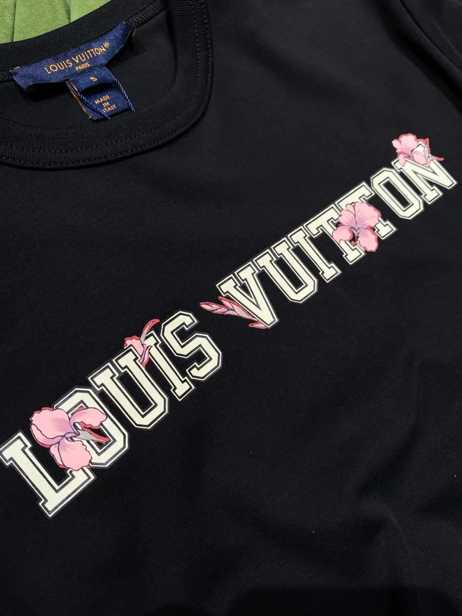 Крупный план надписи Louis Vuitton с розовыми цветами на груди чёрной футболки