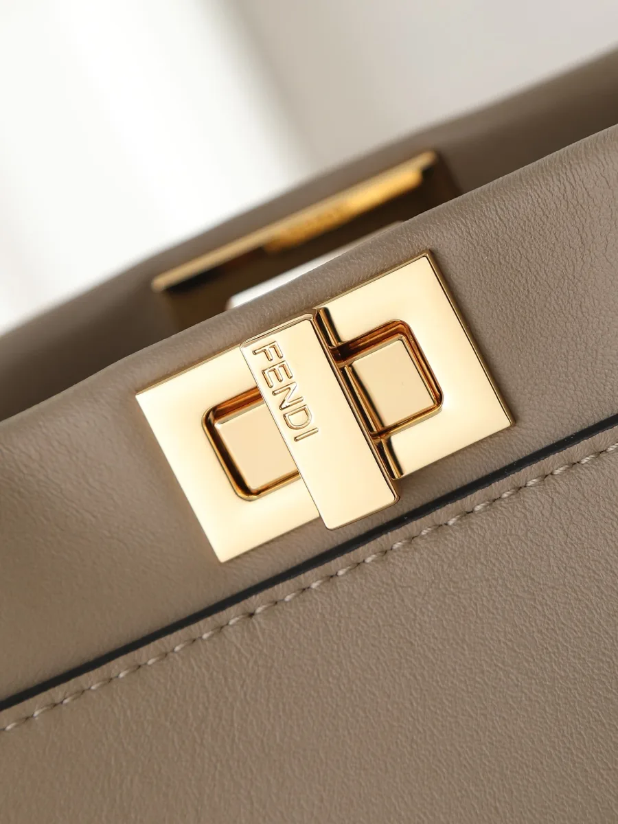Поворотный замок золотистого цвета с гравировкой бренда Fendi крупным планом