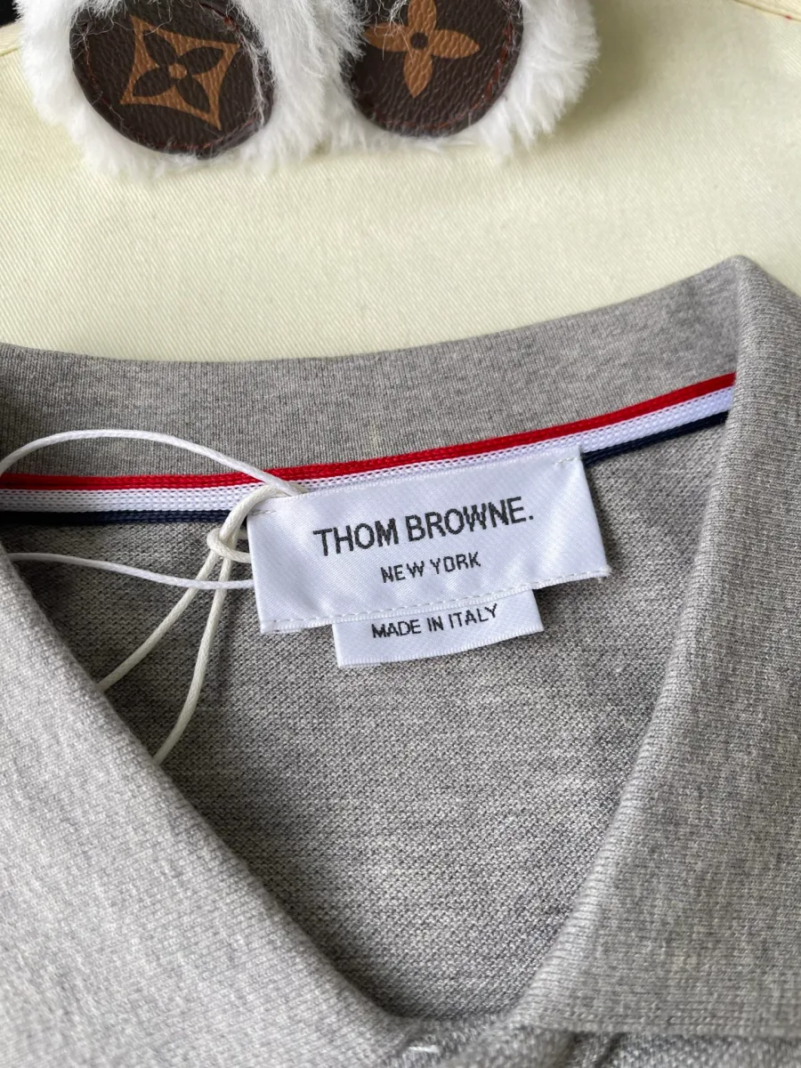 Горловина серого поло с внутренней биркой Thom Browne и трёхцветной лентой