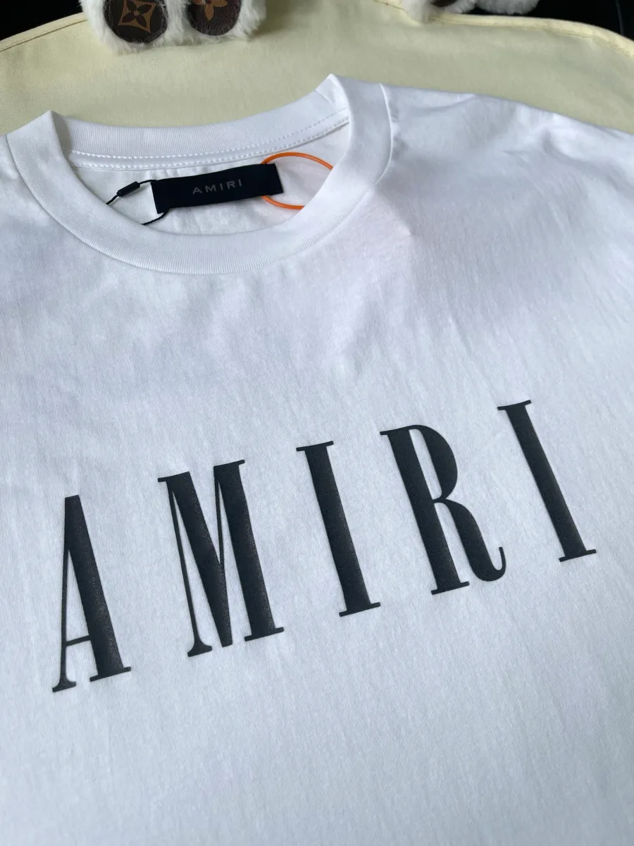 Чёрный контрастный логотип Amiri на груди белой футболки, крупный план