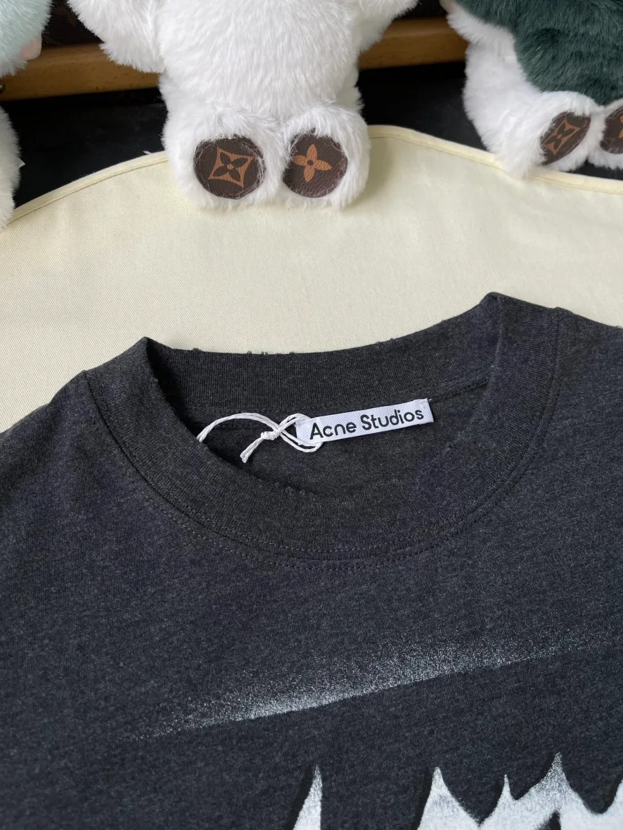 Круглый воротник тёмно-серой футболки с фирменной биркой Acne Studios крупным планом