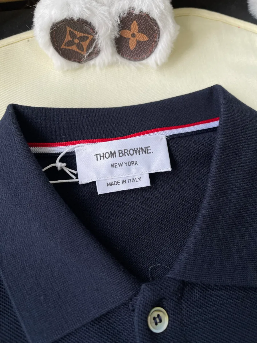 Бирка Thom Browne New York и трёхцветная петля на воротнике тёмно-синего поло