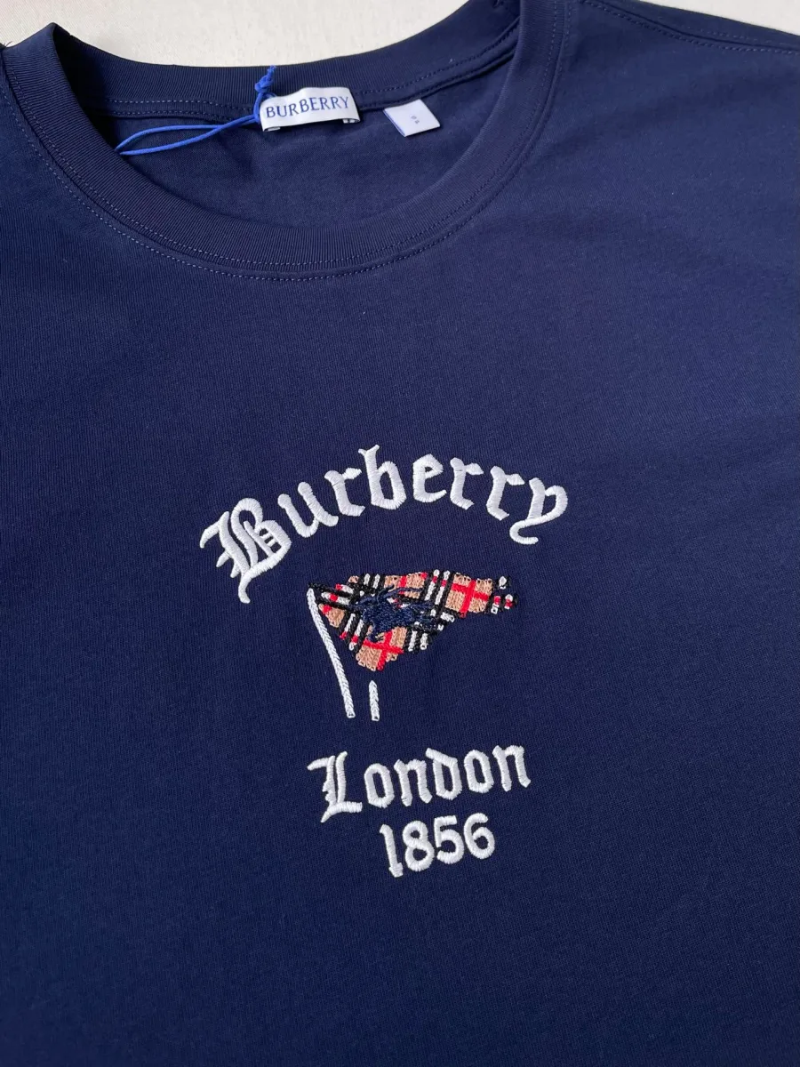 Деталь вышивки на груди: надпись Burberry London 1856 и клетчатый флаг