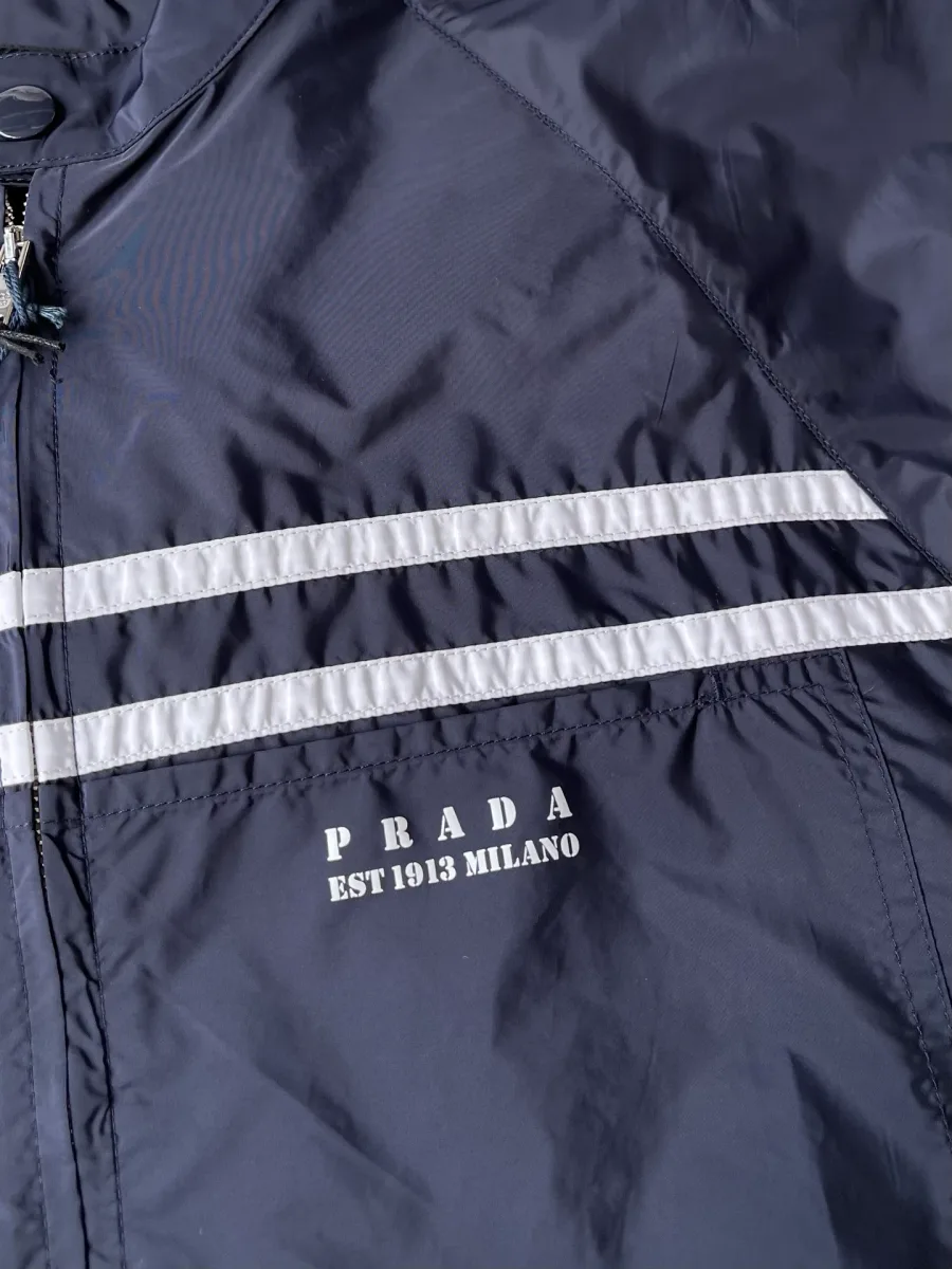 Белые полосы и надпись Prada EST 1913 MILANO на груди крупным планом