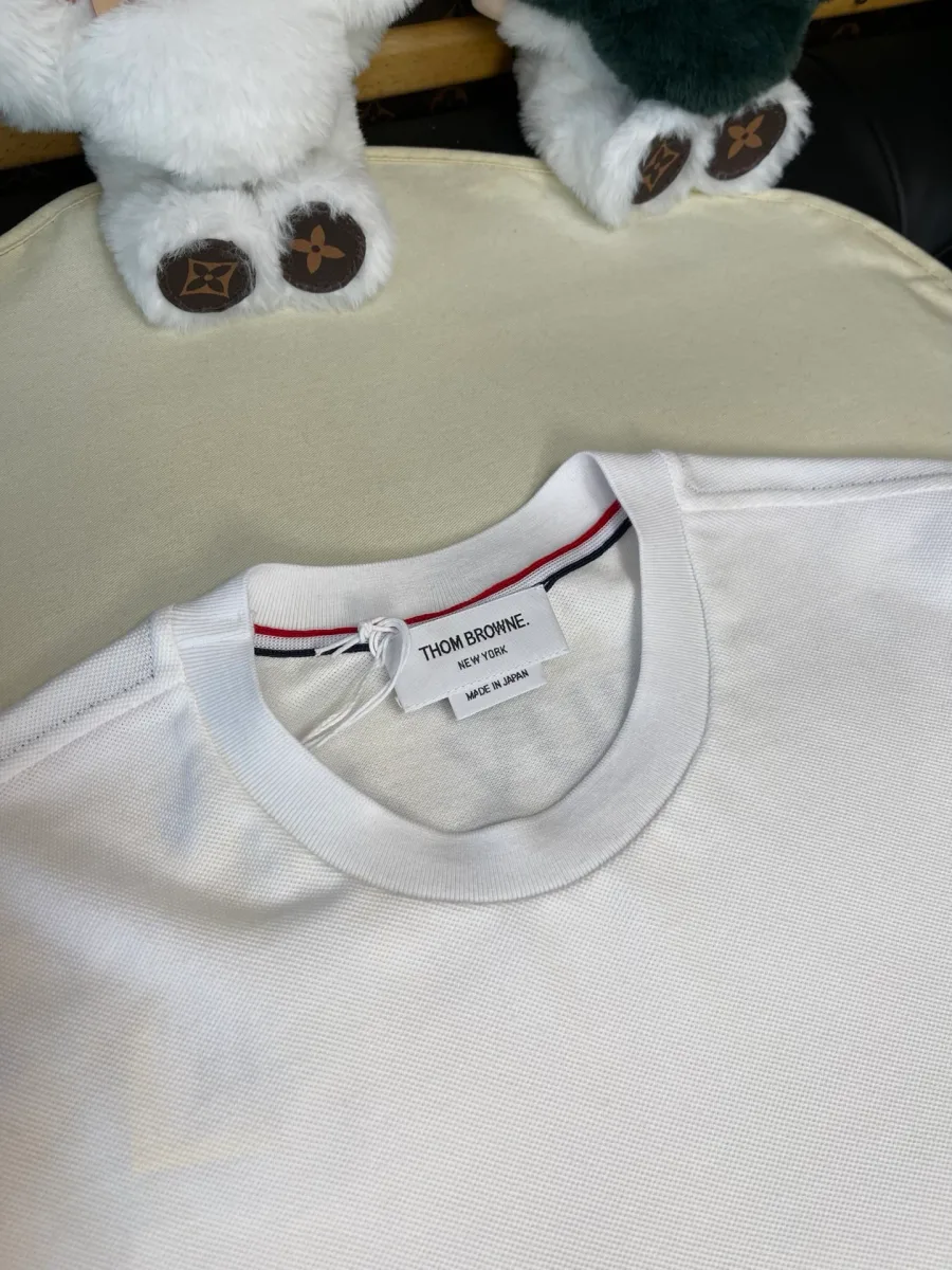Круглый вырез горловины белой футболки и фирменный ярлык Thom Browne