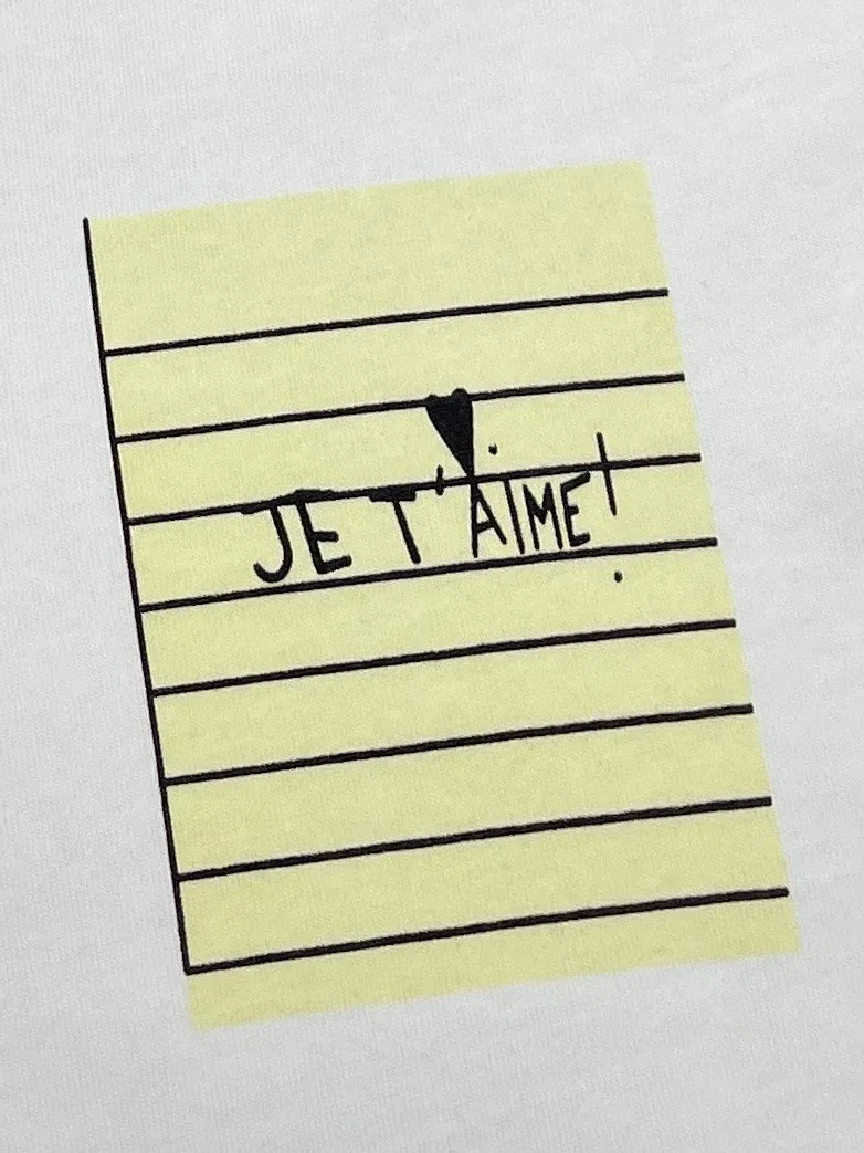 Крупный план принта на груди в виде жёлтого стикера с надписью Je t'aime