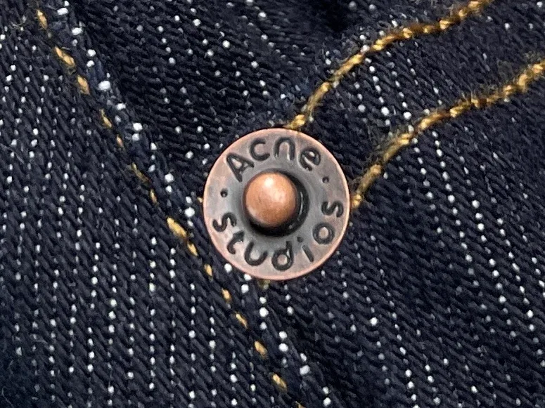Металлическая клёпка с гравировкой Acne Studios крупным планом