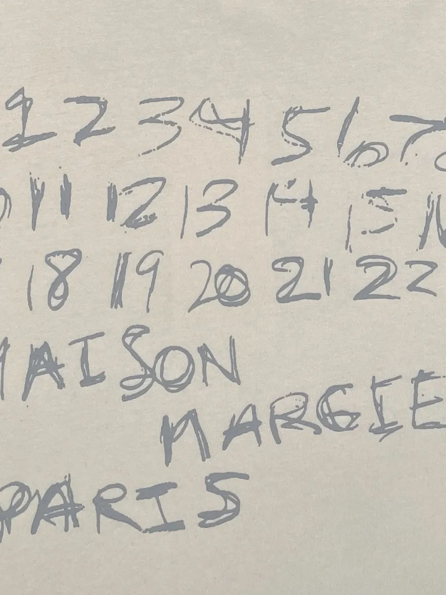 Крупный план серого рукописного числового принта с надписью Maison Margiela Paris