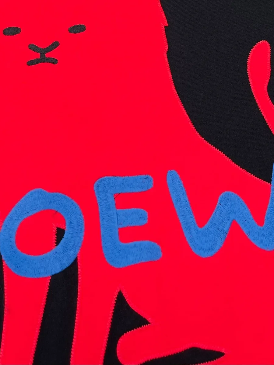 Крупный план контрастного красного принта с синей надписью LOEWE на груди