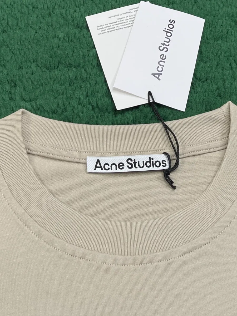 Круглый вырез горловины бежевой футболки с фирменной биркой Acne Studios