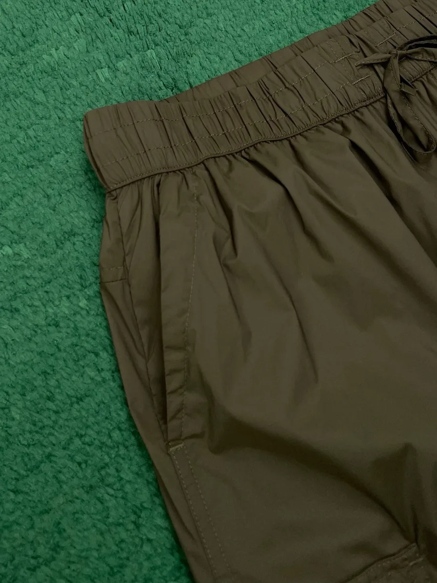 Эластичный пояс на кулиске и врезной боковой карман брюк крупным планом