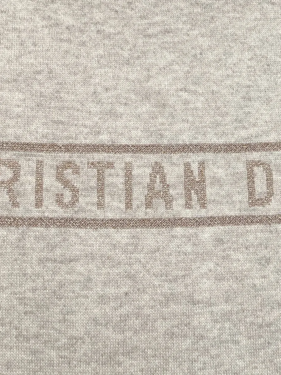 Крупный план вязаной надписи Christian Dior на однотонной стороне изделия