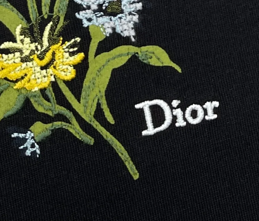 Фрагмент вышитых жёлтых и голубых цветов с надписью Dior крупным планом
