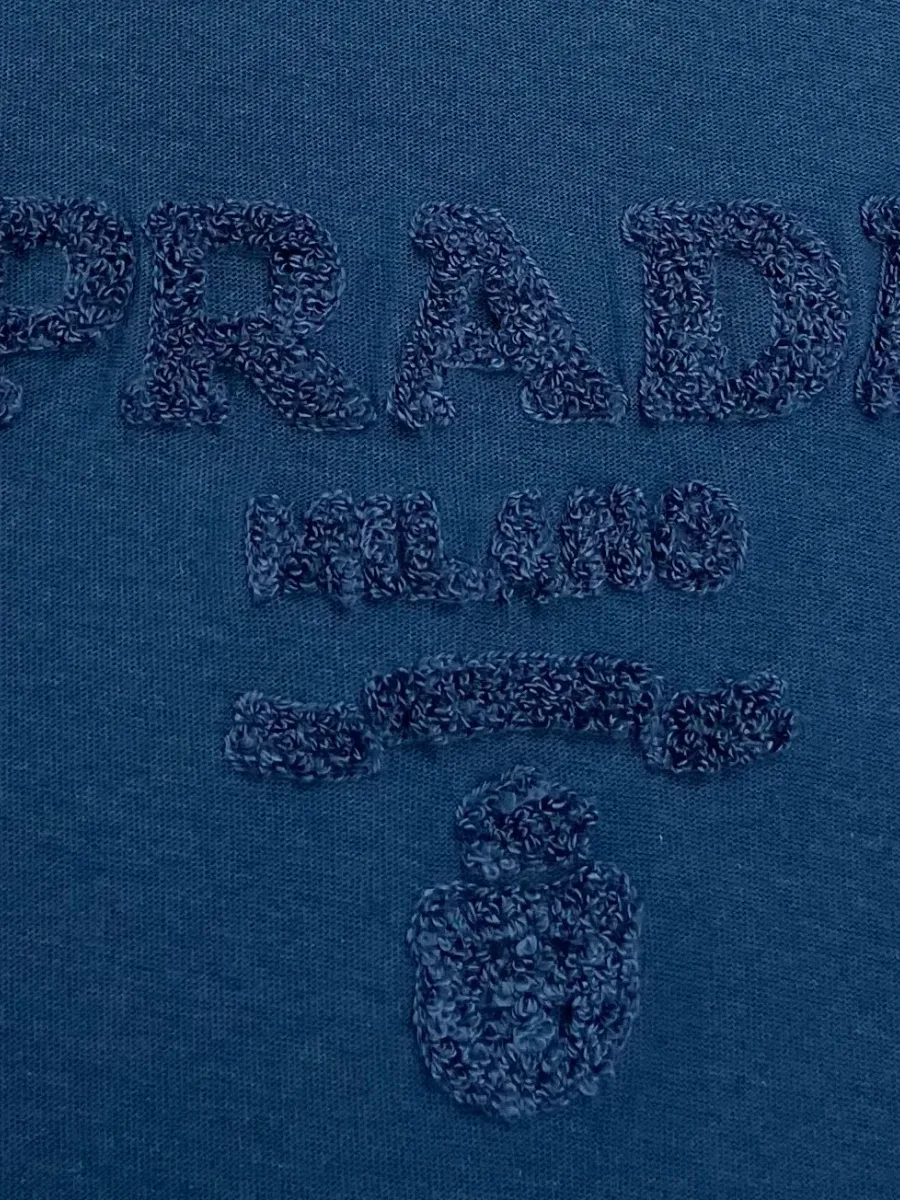 Деталь объёмной бархатистой надписи Prada Milano на груди