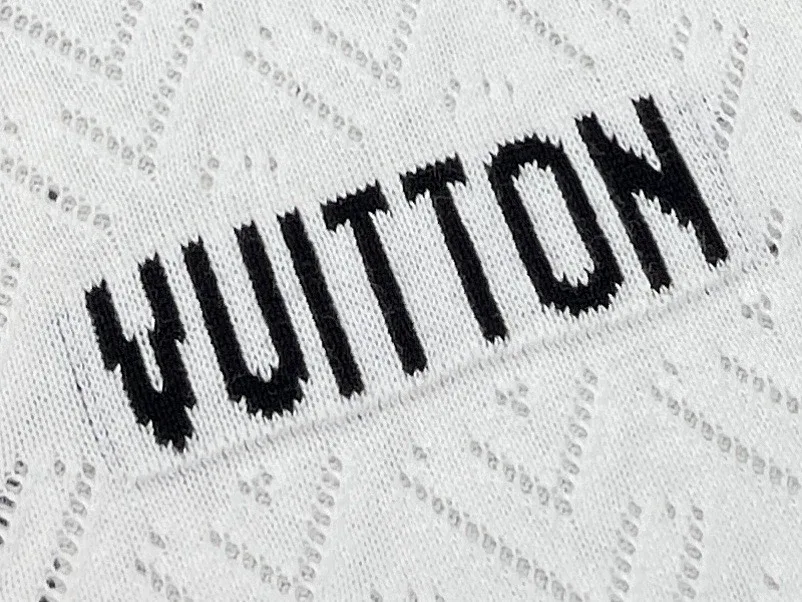 Деталь контрастной чёрной вышивки Vuitton на белом фактурном трикотаже