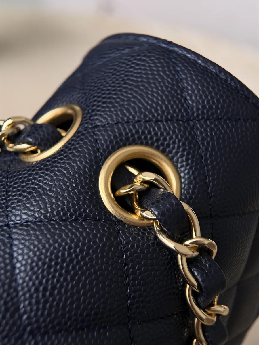 Крупный план золотистых люверсов и цепочки на темно-синей сумке Chanel