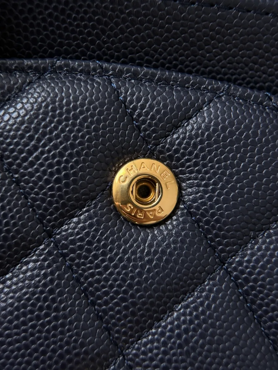 Крупный план золотистой кнопки с гравировкой Chanel Paris на коже