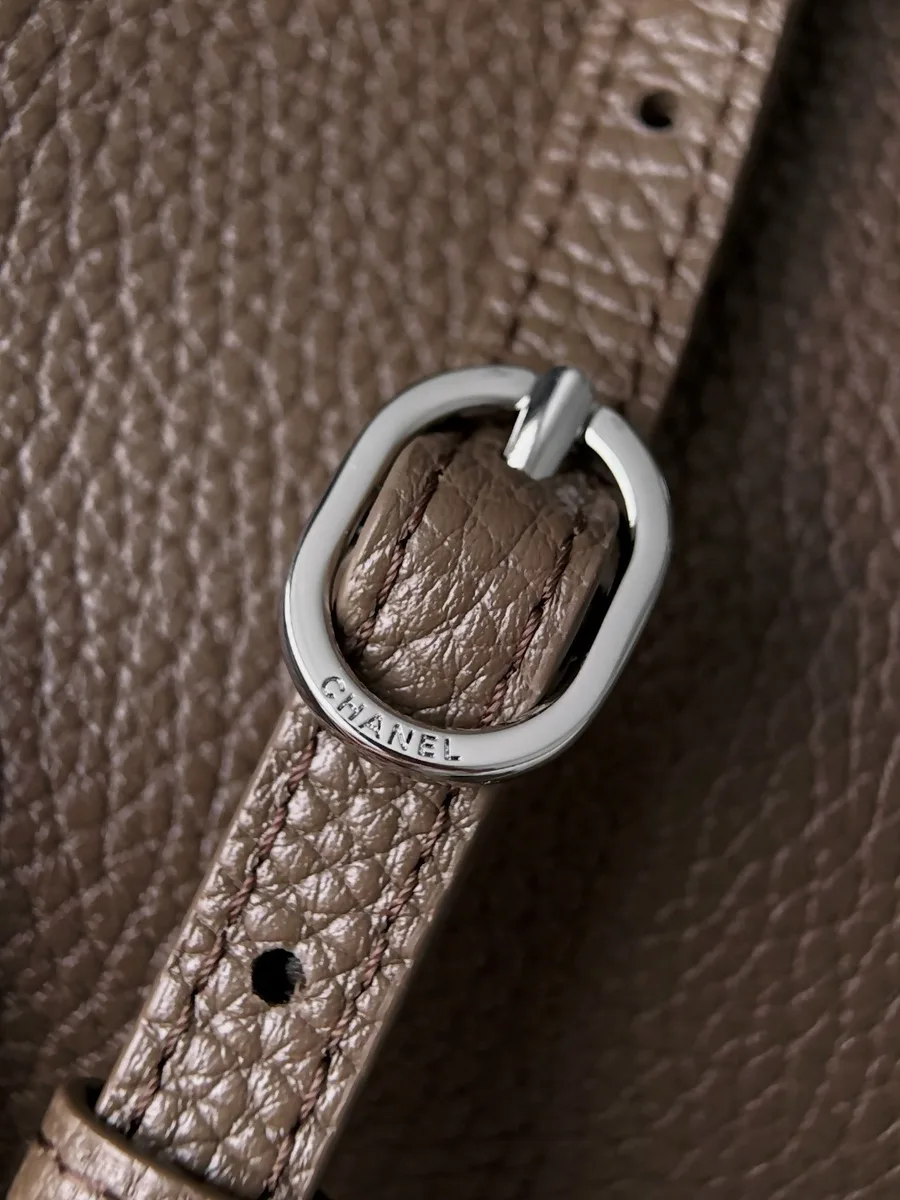 Крупный план серебристой пряжки с гравировкой Chanel на кожаном ремне
