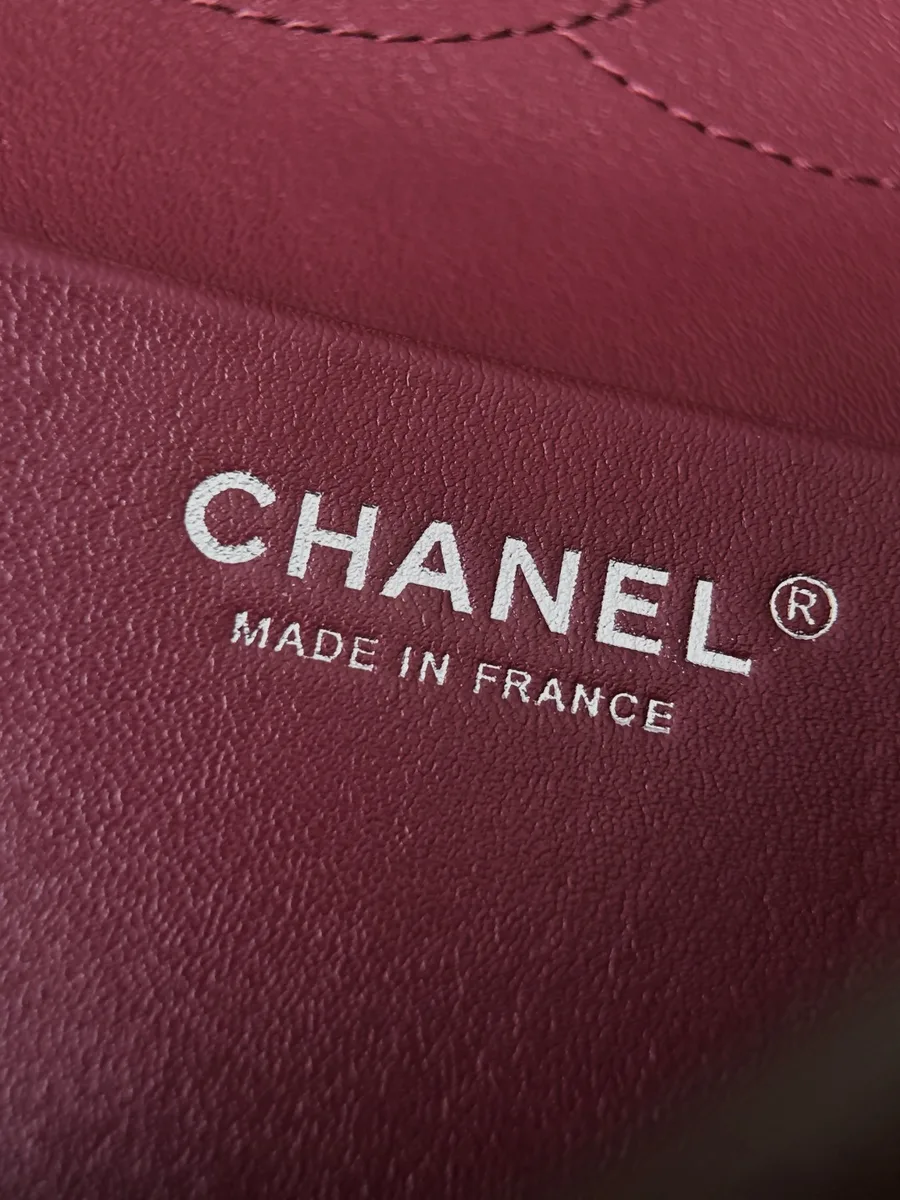 Крупный план серебристого тиснения Chanel Made in France на бордовой коже