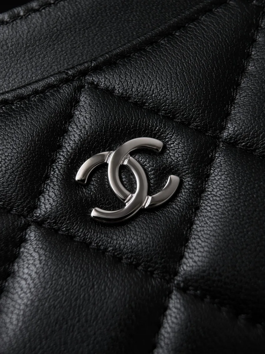 Крупный план серебристого логотипа CC на черной стеганой коже картхолдера Chanel