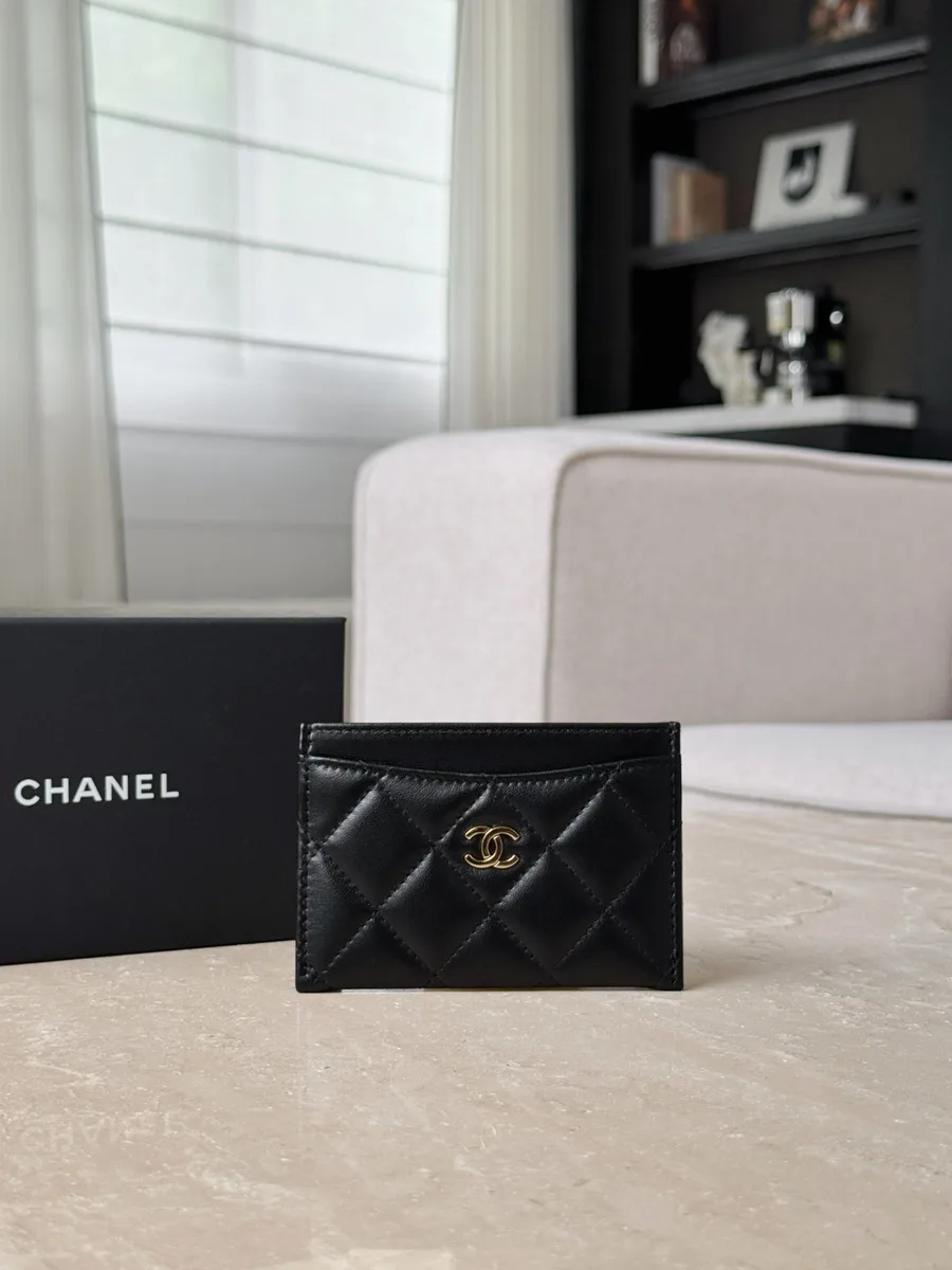 Чёрный стёганый картхолдер Chanel с золотистым логотипом CC на фоне фирменной коробки