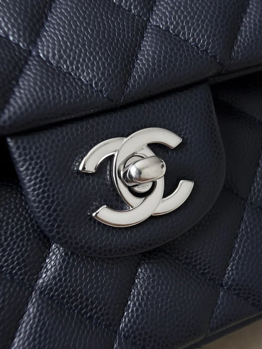 Крупный план серебристого поворотного замка CC на синей сумке Chanel