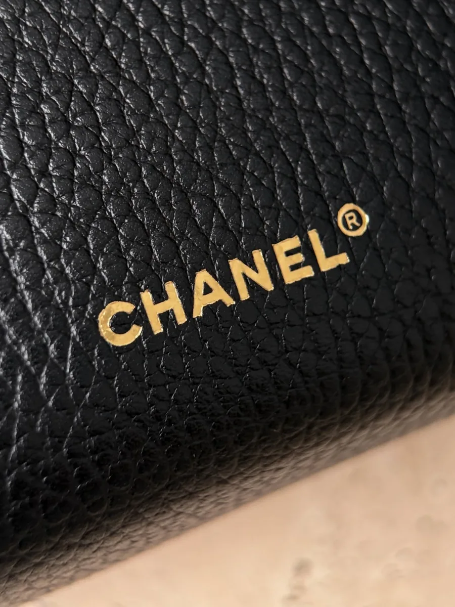 Крупный план золотистого тиснения Chanel на задней панели сумки