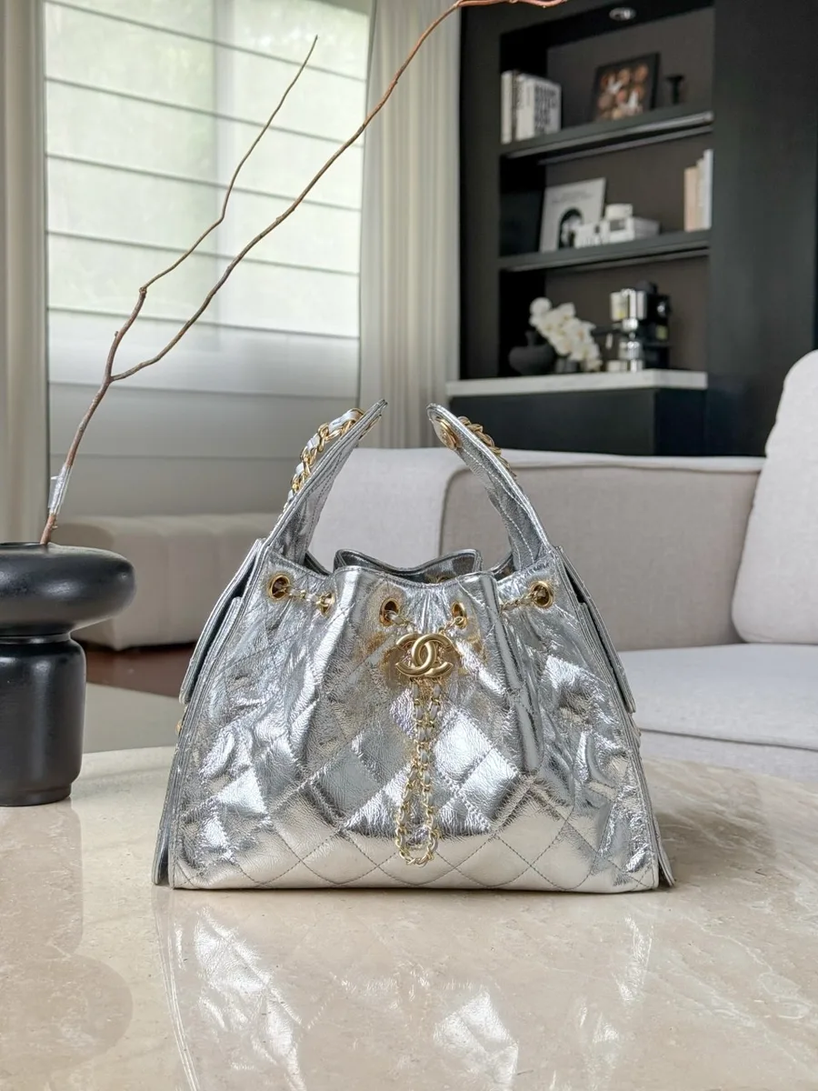 Серебристая сумка-хобо Chanel Hobo из стеганой кожи на светлой поверхности