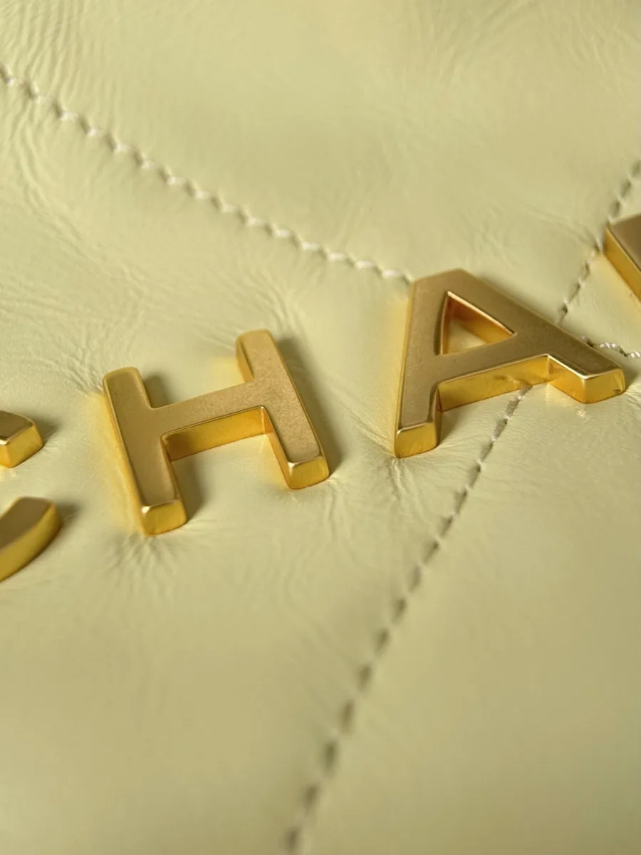 Крупный план золотистых букв Chanel на стёганой коже