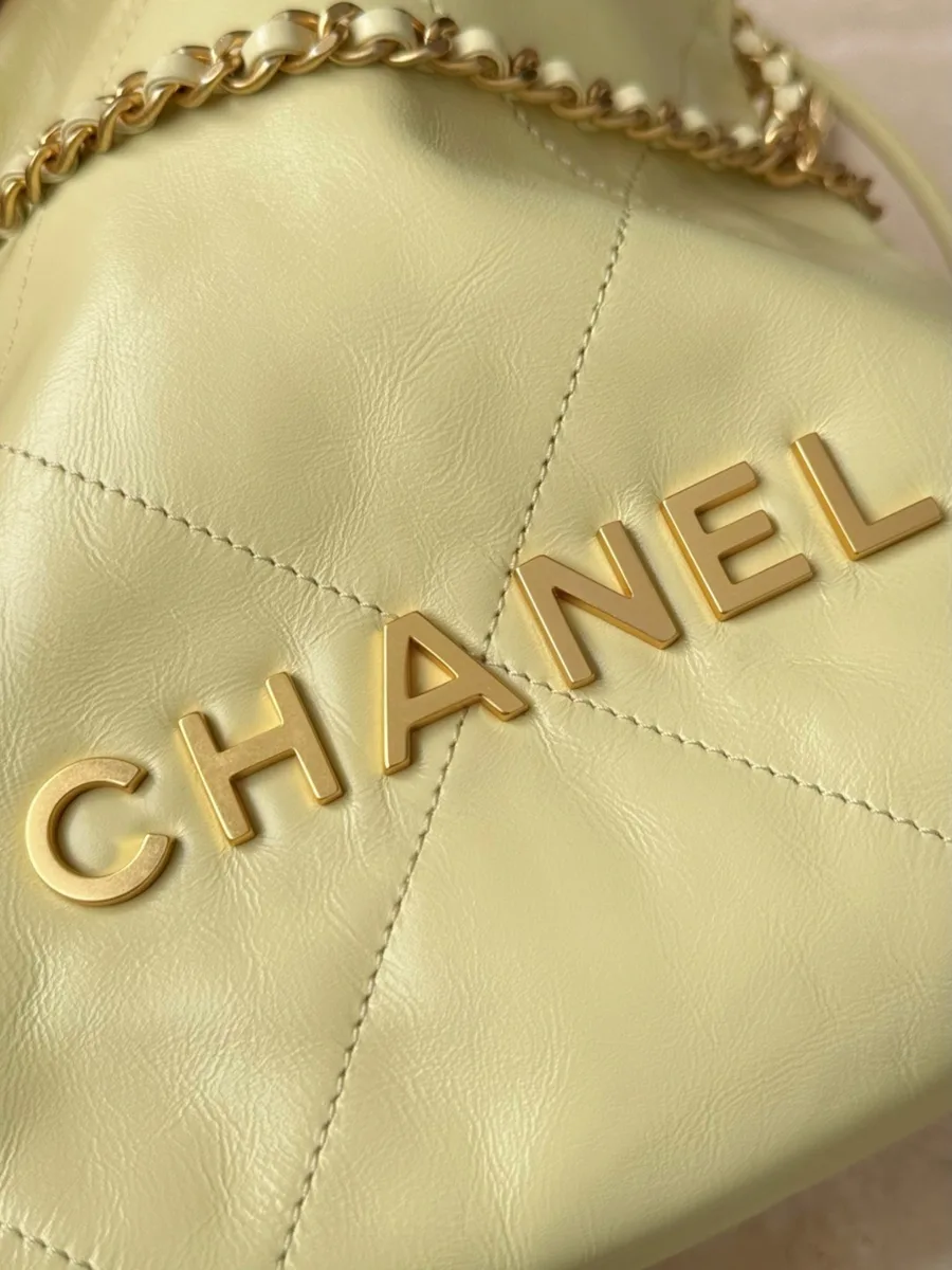 Крупный план золотистых букв логотипа Chanel на жёлтой коже