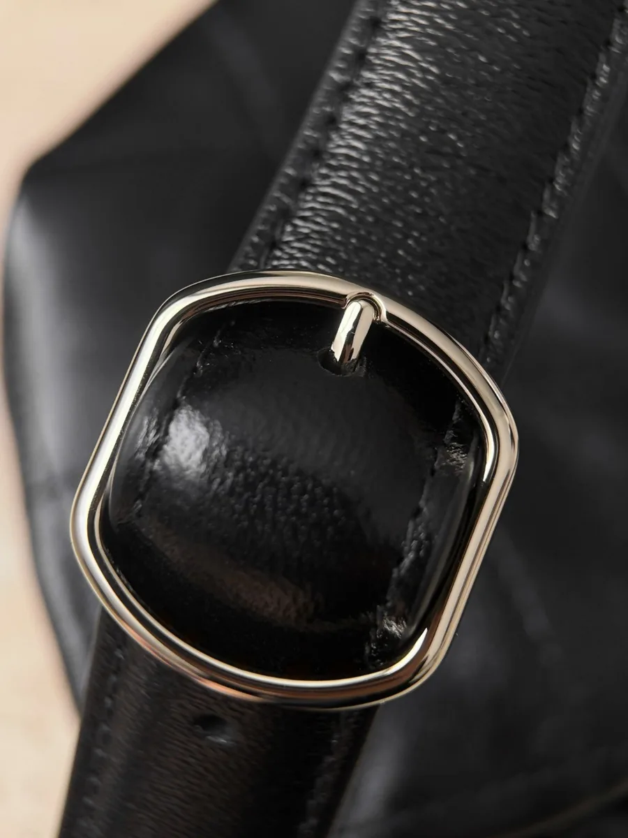 Золотистая металлическая пряжка на кожаном плечевом ремне