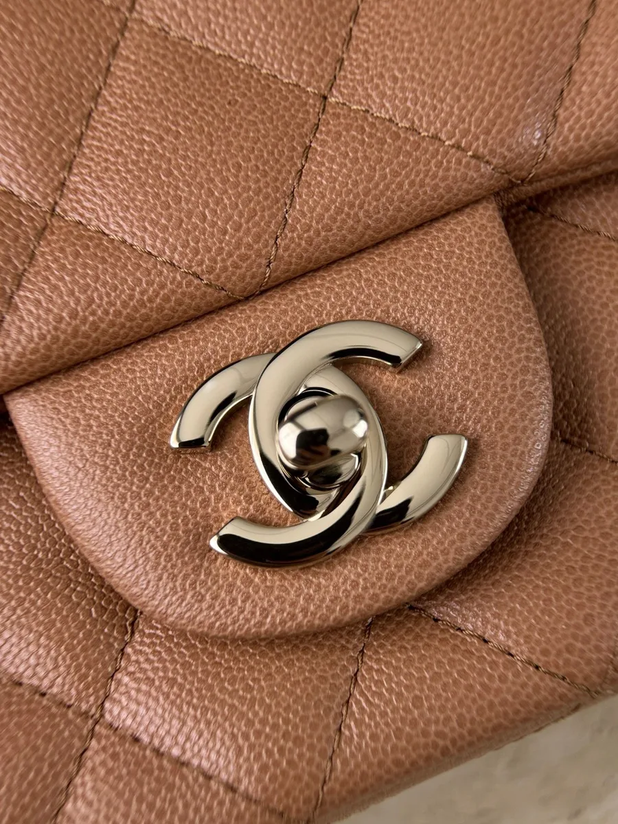 Крупный план золотистого поворотного замка CC на коричневой коже сумки Chanel