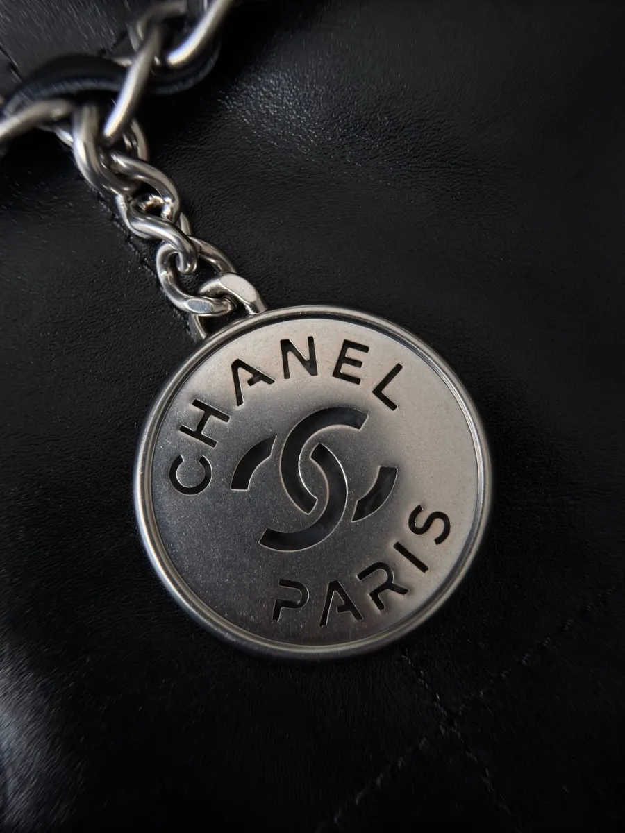 Крупный план серебристого круглого медальона с логотипом Chanel Paris