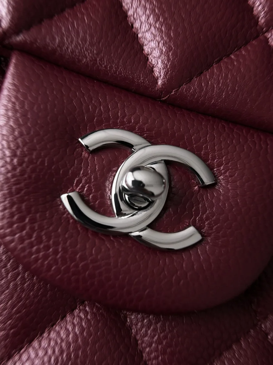 Серебристый поворотный замок в виде логотипа CC на бордовой сумке Chanel