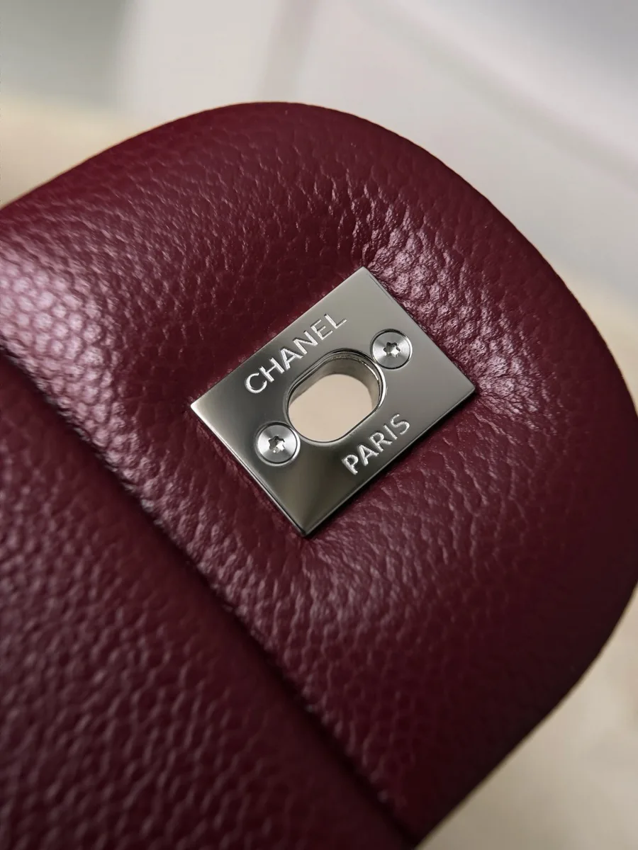 Обратная сторона замка с гравировкой Chanel Paris на бордовой сумке