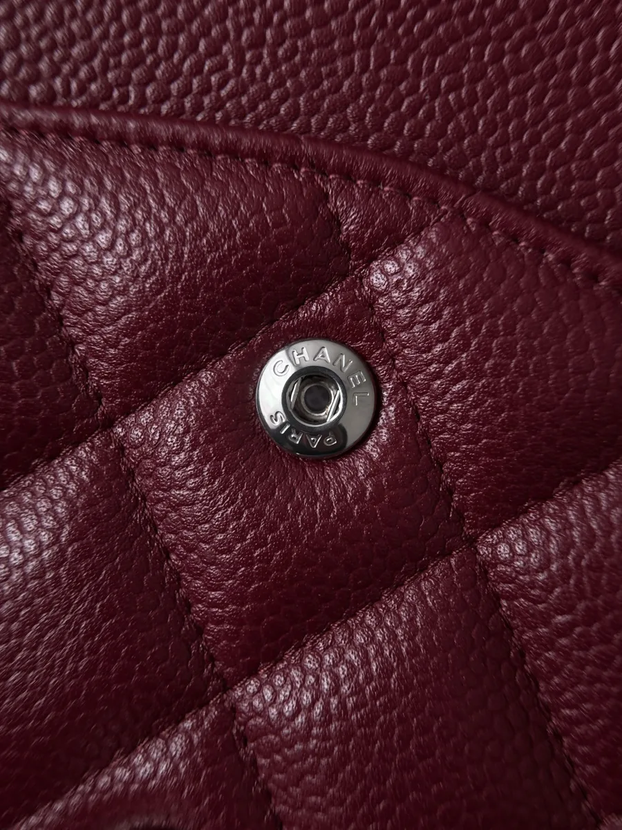 Кнопка с гравировкой Chanel Paris и текстура зернистой кожи бордовой сумки