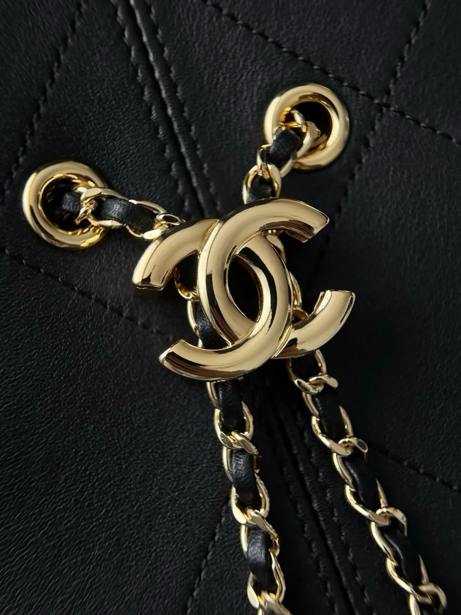Крупный план золотистой подвески в виде логотипа CC на цепочке чёрной сумки Chanel