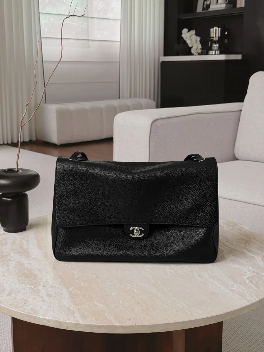 Чёрная кожаная сумка Chanel Classic Flap на столе, вид спереди