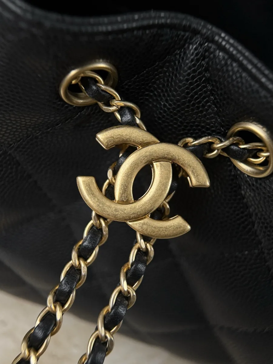 Золотистая металлическая монограмма CC на шнурке сумки Chanel, крупный план.