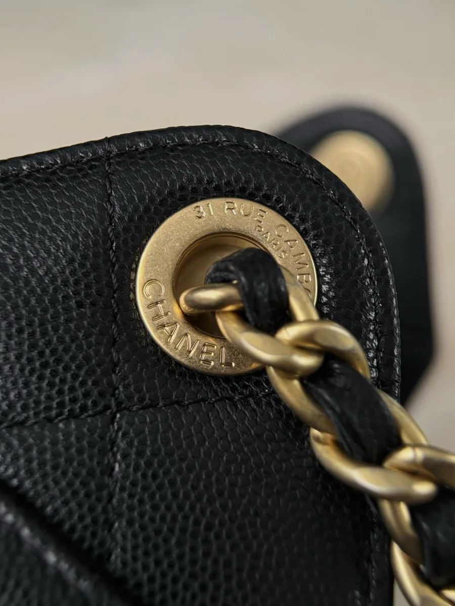 Золотистый люверс с гравировкой Chanel и цепочка, крупный план.
