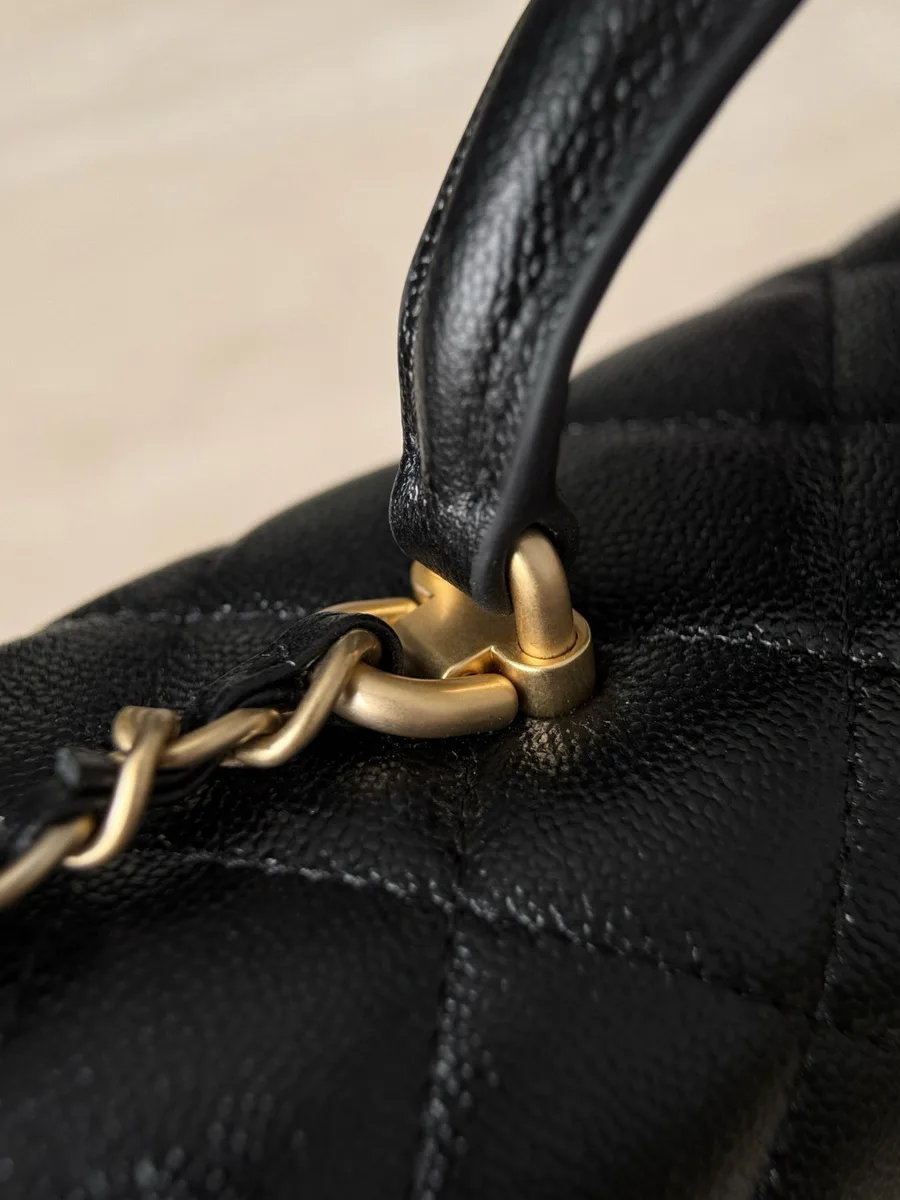 Крепление кожаной ручки черной сумки Chanel крупным планом