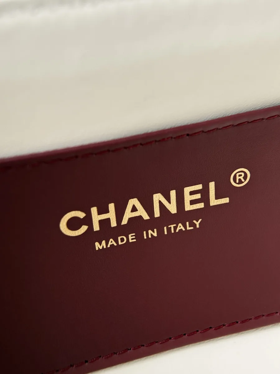 Крупный план золотистого тиснения Chanel Made in Italy на бордовой коже
