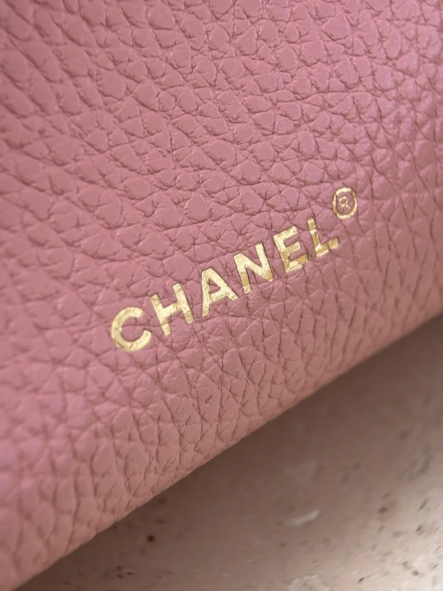 Крупный план золотистого тиснения Chanel на розовой коже