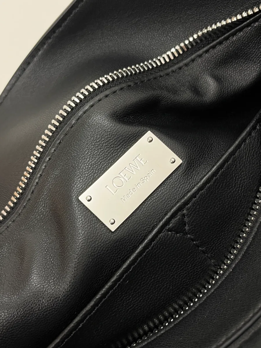 Серебристая металлическая пластина с гравировкой Loewe внутри сумки