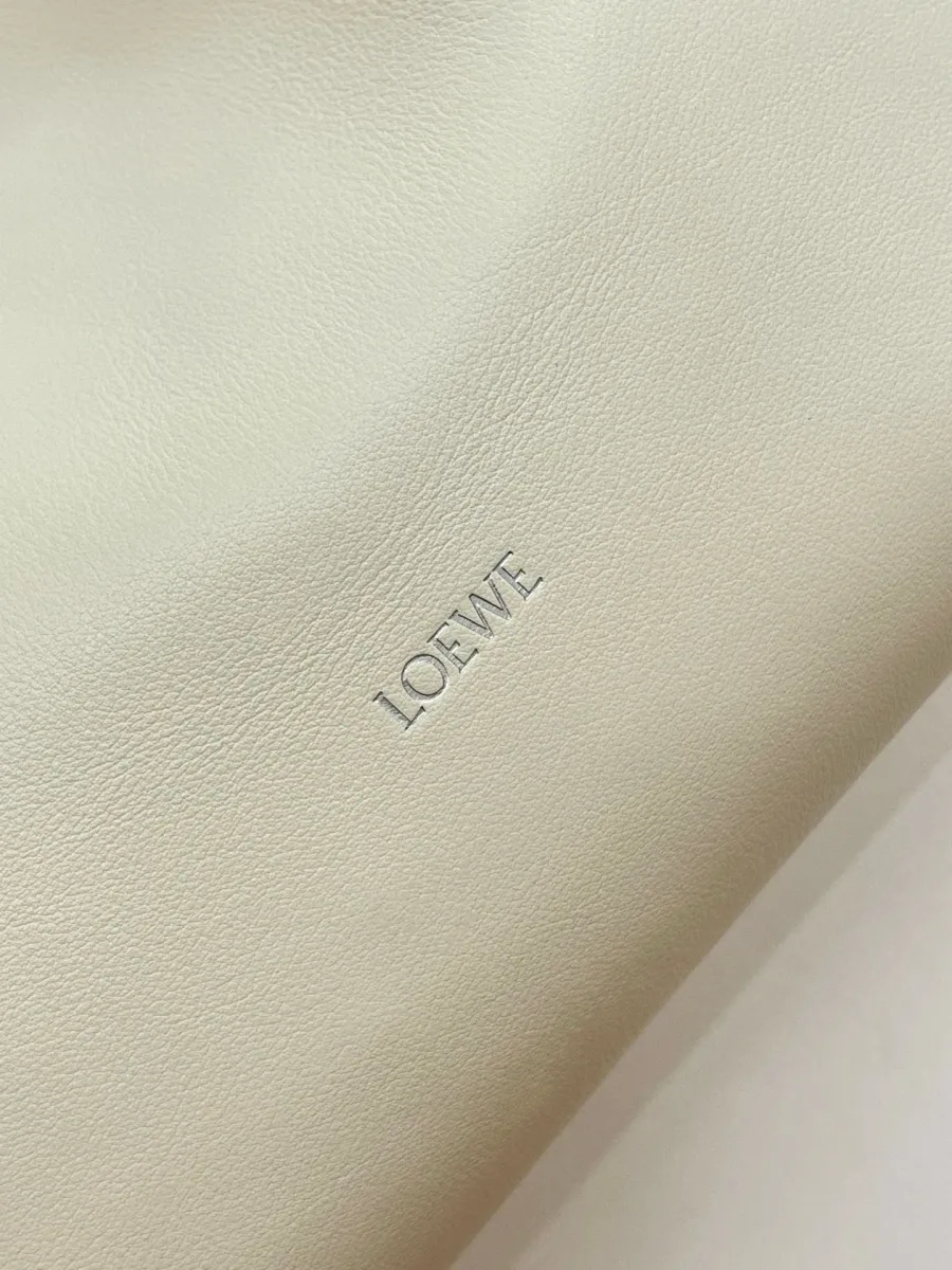 Тиснёный серебристый логотип Loewe на гладкой белой коже крупным планом