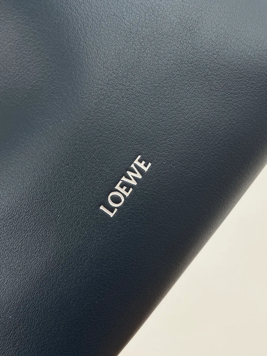 Крупный план серебристого тиснения логотипа Loewe на синей коже